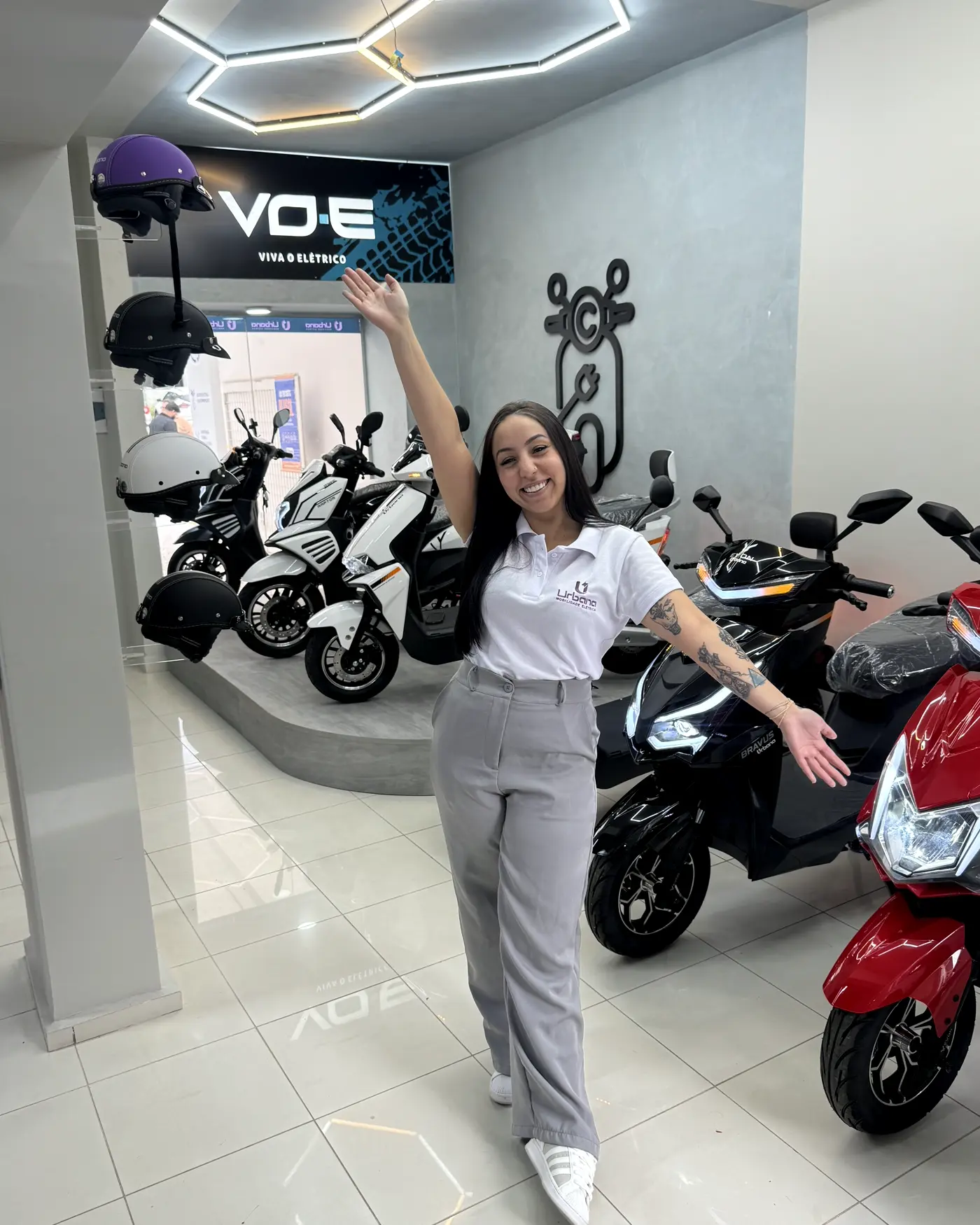 Consultora da MotoChefe no showroom, entre as scooters elétricas expostas